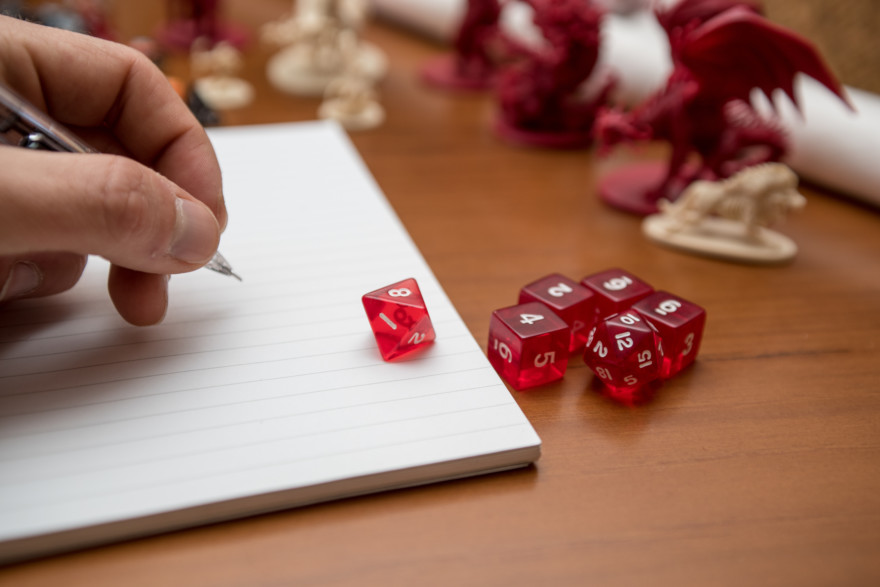 Pen, Notebook And Dices To Play Role Game Like Dungeons And Dragons. Writing With The Mechanical Pencil On The Notebook.